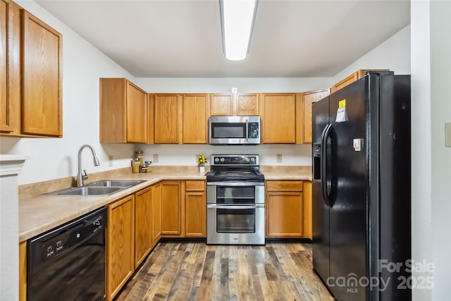 925 Skywatch Ln, Monroe, NC 28112 - kitchen with black appliances, a sink, wood finished floors, light countertops, and brown cabinets
