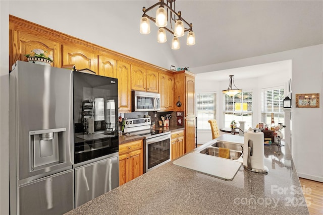 1530 Danlee Dr, Lancaster, SC 29720 - kitchen with appliances with stainless steel finishes, decorative light fixtures, lofted ceiling, brown cabinets, and decorative backsplash