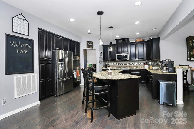 7434 Dover Mill Ln SW, Concord, NC 28025 - kitchen featuring stainless steel appliances, dark cabinetry, a kitchen bar, and recessed lighting