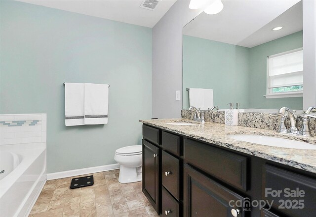7434 Dover Mill Ln SW, Concord, NC 28025 - full bath with double vanity, baseboards, a garden tub, toilet, and stone finish flooring