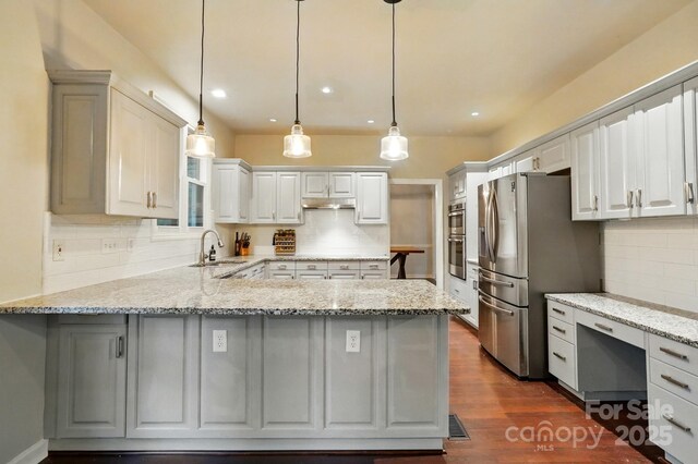 8708 Piccone Brook Ln, Charlotte, NC 28216 - kitchen featuring appliances with stainless steel finishes, a sink, a peninsula, backsplash, and light stone countertops