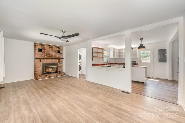 3595 Mt Holly Rd, Edgemoor, SC 29712 - unfurnished living room with stacked washer and clothes dryer, electric panel, a ceiling fan, a sink, and light wood finished floors
