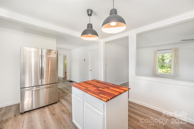 3595 Mt Holly Rd, Edgemoor, SC 29712 - kitchen with freestanding refrigerator, butcher block countertops, white cabinets, light wood-style floors, and decorative light fixtures