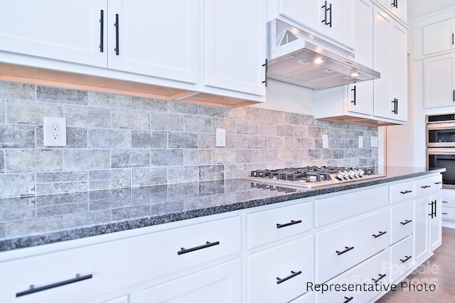 4178 Millstream Rd, Denver, NC 28037 - kitchen with under cabinet range hood, white cabinetry, dark stone counters, decorative backsplash, and appliances with stainless steel finishes