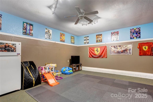 1209 Danielle Downs Ct SE, Concord, NC 28025 - playroom with rail lighting, carpet floors, a ceiling fan, a textured ceiling, and a textured wall