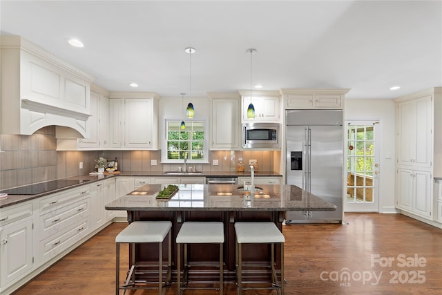 7213 Lancer Dr, Charlotte, NC 28226 - kitchen with built in appliances, a sink, a kitchen breakfast bar, a center island with sink, and dark wood finished floors