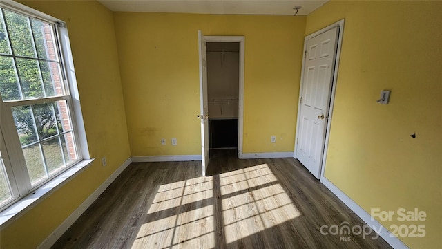 4227 Kiser Woods Dr SW, Concord, NC 28025 - unfurnished bedroom featuring dark wood-type flooring, multiple windows, baseboards, and a spacious closet