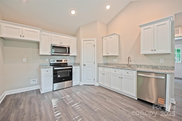 1028 Gibson St, Albemarle, NC 28001 - kitchen with stainless steel appliances, lofted ceiling, a sink, white cabinetry, and light wood-type flooring