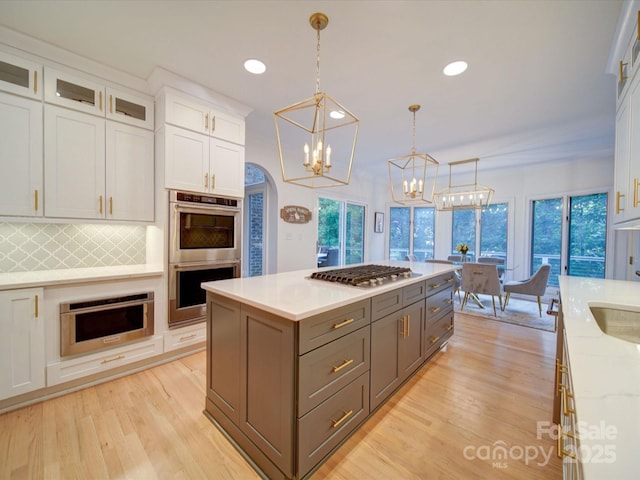 15708 Eagleview Dr, Charlotte, NC 28278 - kitchen featuring appliances with stainless steel finishes, white cabinets, light wood finished floors, tasteful backsplash, and pendant lighting