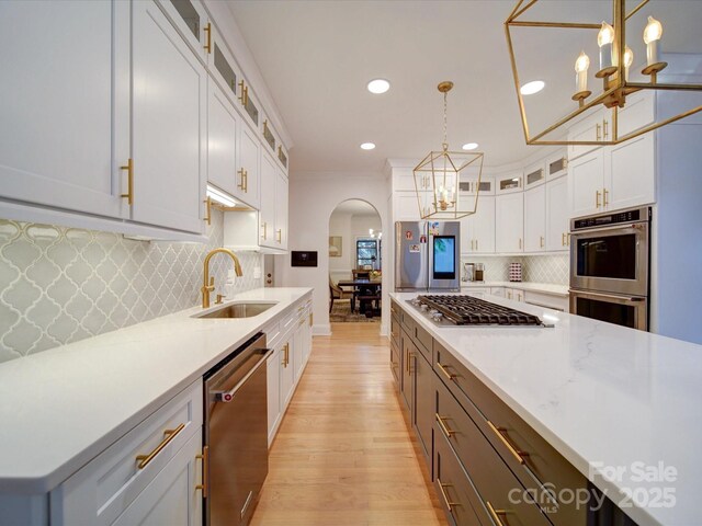 15708 Eagleview Dr, Charlotte, NC 28278 - kitchen featuring appliances with stainless steel finishes, a sink, a chandelier, arched walkways, and white cabinetry