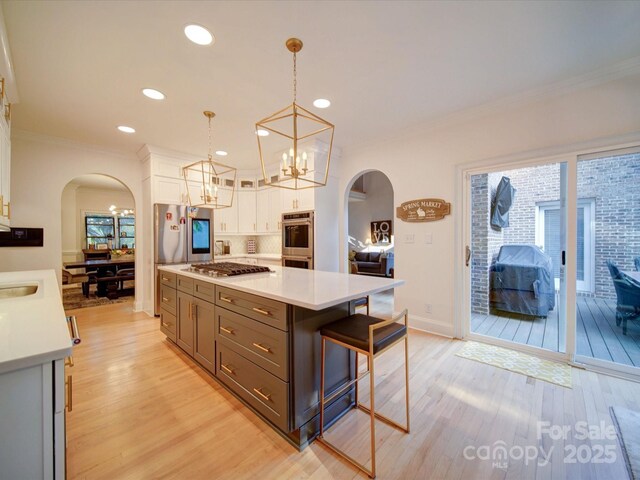 15708 Eagleview Dr, Charlotte, NC 28278 - kitchen with arched walkways, white cabinets, stainless steel appliances, light wood-type flooring, and ornamental molding