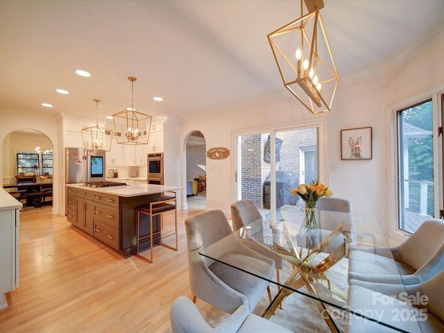 15708 Eagleview Dr, Charlotte, NC 28278 - dining room featuring arched walkways, a chandelier, light wood-style floors, crown molding, and recessed lighting