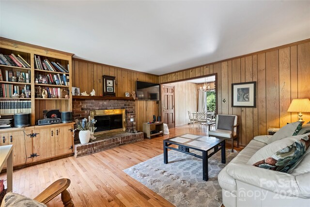 6434 Sardis Rd, Charlotte, NC 28270 - living room with wooden walls, light wood finished floors, a chandelier, and a brick fireplace