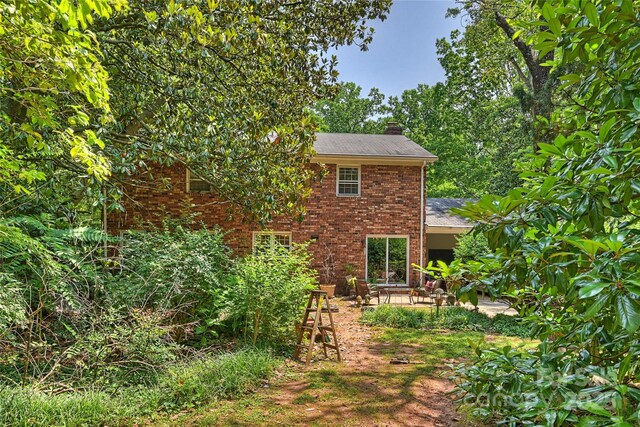 6434 Sardis Rd, Charlotte, NC 28270 - view of side of home featuring a chimney, brick siding, a patio, and a shingled roof