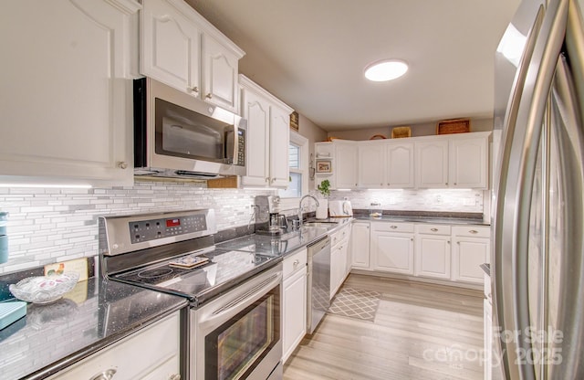 110 Spring Path, Hendersonville, NC 28739 - kitchen featuring stainless steel appliances, white cabinetry, a sink, light wood-type flooring, and decorative backsplash