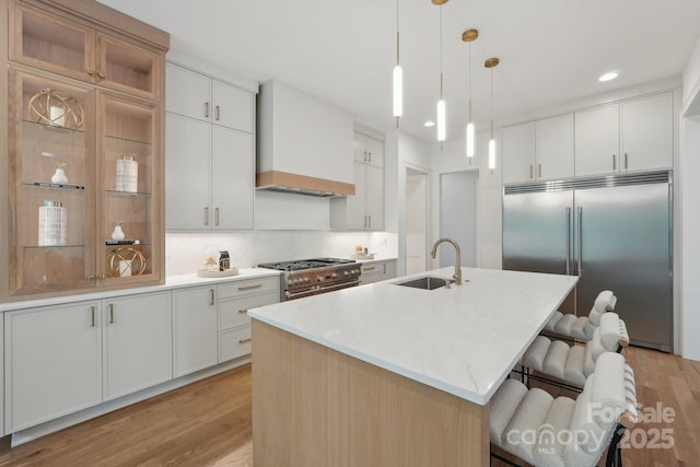 213 Crest Ct, Weddington, NC 28104 - kitchen with premium appliances, a sink, custom range hood, light wood-style flooring, and a kitchen breakfast bar