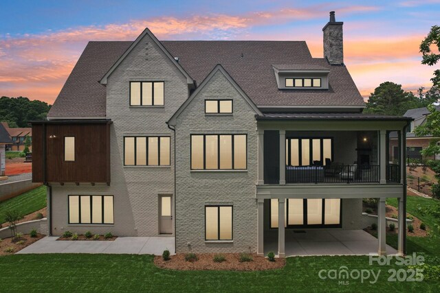 213 Crest Ct, Weddington, NC 28104 - back of property at dusk with a patio, a chimney, a yard, and roof with shingles