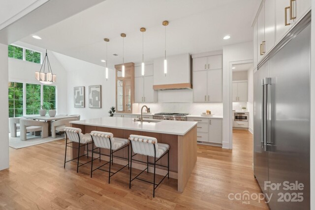 213 Crest Ct, Weddington, NC 28104 - kitchen featuring stainless steel built in refrigerator, custom exhaust hood, a sink, a kitchen breakfast bar, and light wood-style floors