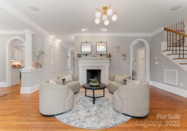 901 Hartford Ave, Charlotte, NC 28209 - living room with arched walkways, stairway, light wood-style flooring, a fireplace, and ornamental molding