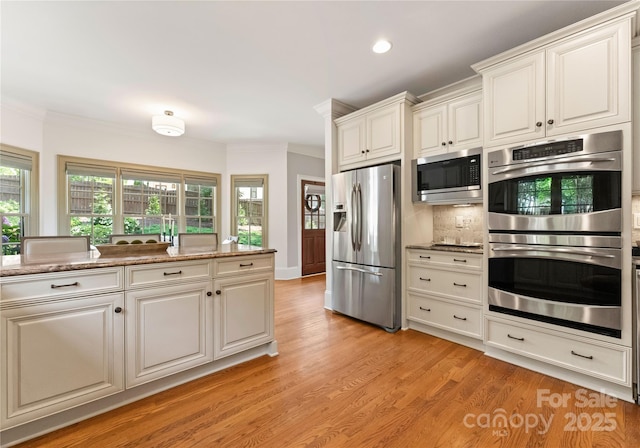 901 Hartford Ave, Charlotte, NC 28209 - kitchen featuring stainless steel appliances, crown molding, light wood finished floors, white cabinetry, and light stone counters