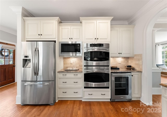 901 Hartford Ave, Charlotte, NC 28209 - kitchen with stainless steel appliances, wine cooler, stone counters, arched walkways, and ornamental molding