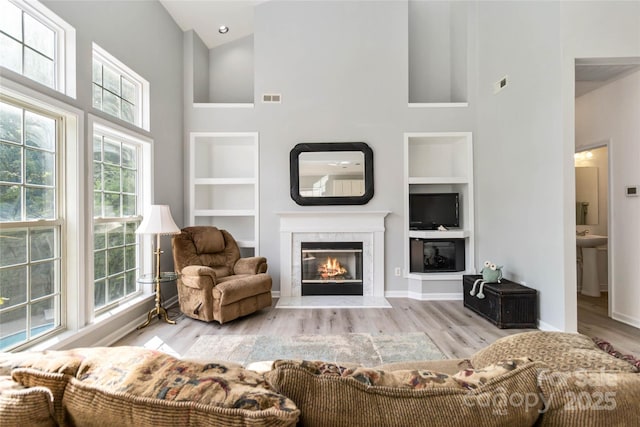 7704 Ninth Fairway Ln, Mint Hill, NC 28227 - living room with built in features, a towering ceiling, a fireplace, and wood finished floors