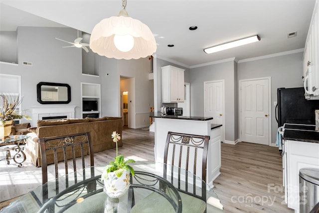 7704 Ninth Fairway Ln, Mint Hill, NC 28227 - kitchen with dark countertops, light wood-style flooring, white cabinetry, ornamental molding, and a ceiling fan