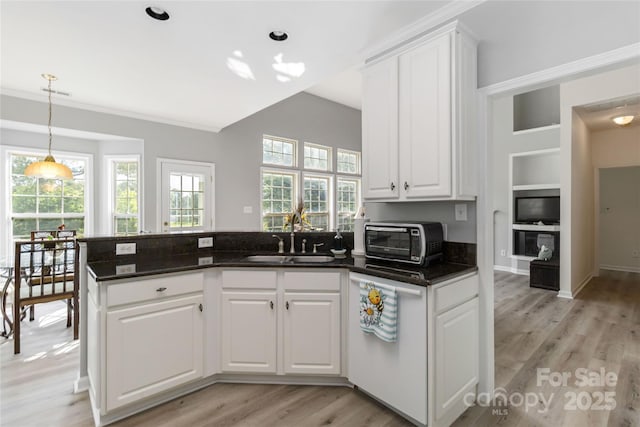 7704 Ninth Fairway Ln, Mint Hill, NC 28227 - kitchen featuring a peninsula, white cabinets, light wood-style floors, ornamental molding, and hanging light fixtures