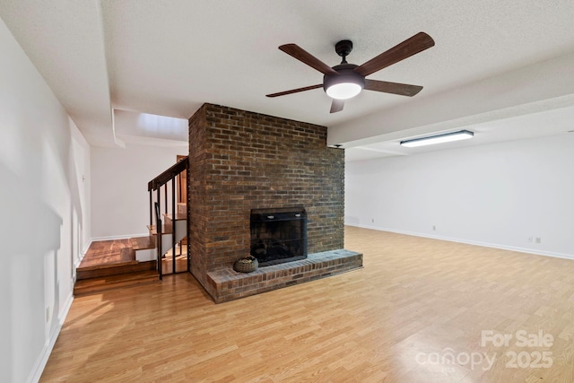 204 Woodfield Dr, Asheville, NC 28803 - unfurnished living room with light wood finished floors, stairway, ceiling fan, and a brick fireplace