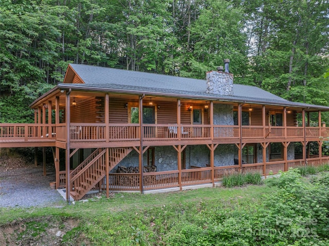 47 Tammy Dr, Maggie Valley, NC 28751 - view of front of house featuring log exterior, a chimney, stone siding, a deck, and roof with shingles