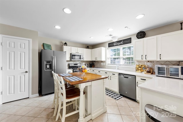 4612 Maple Crest Pl, Harrisburg, NC 28075 - kitchen with stainless steel appliances, tasteful backsplash, light tile patterned flooring, white cabinets, and recessed lighting