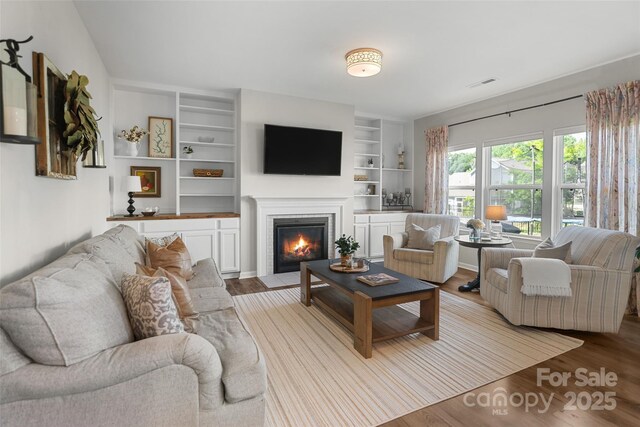 1826 Goodheart Ln, York, SC 29745 - living room featuring a fireplace with flush hearth, wood finished floors, and built in shelves