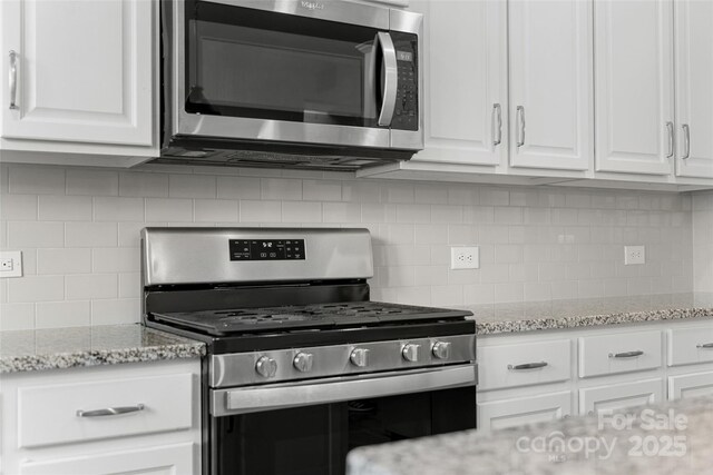 1826 Goodheart Ln, York, SC 29745 - kitchen featuring appliances with stainless steel finishes, tasteful backsplash, white cabinetry, and light stone counters