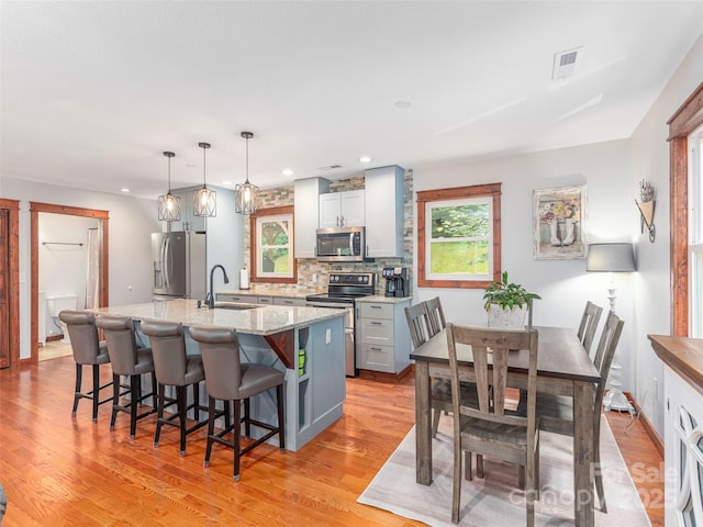 1903 Mauney Cove Rd, Waynesville, NC 28786 - kitchen with stainless steel appliances, light wood-type flooring, an island with sink, decorative backsplash, and a breakfast bar