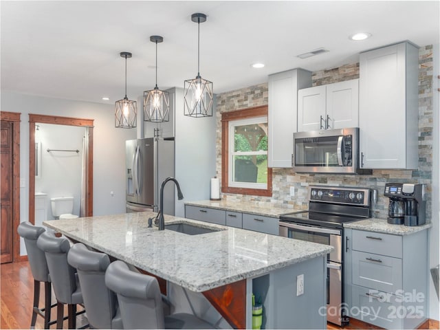1903 Mauney Cove Rd, Waynesville, NC 28786 - kitchen featuring appliances with stainless steel finishes, an island with sink, backsplash, light stone counters, and recessed lighting