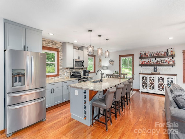1903 Mauney Cove Rd, Waynesville, NC 28786 - kitchen featuring stainless steel appliances, light wood-style flooring, light stone counters, a kitchen breakfast bar, and recessed lighting