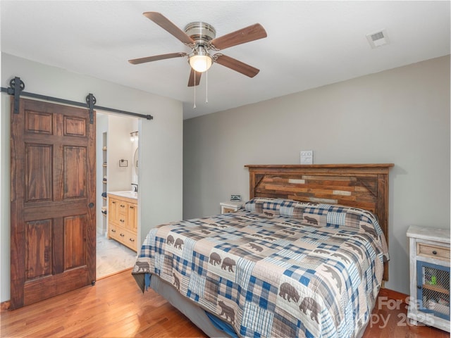 1903 Mauney Cove Rd, Waynesville, NC 28786 - bedroom featuring light wood-style floors, a barn door, a ceiling fan, and ensuite bath