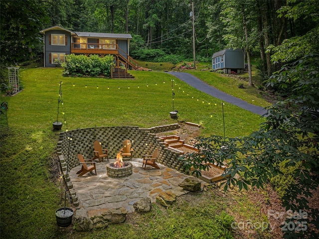 1903 Mauney Cove Rd, Waynesville, NC 28786 - view of green lawn featuring an outdoor fire pit, stairway, a patio, a wooden deck, and a forest view