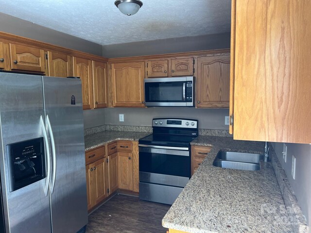 22 Congress St, Granite Falls, NC 28630 - kitchen with appliances with stainless steel finishes, brown cabinets, dark wood-style floors, and a textured ceiling