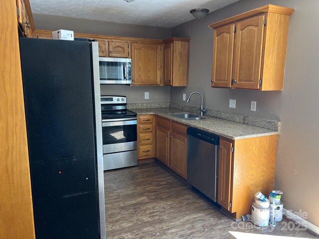 22 Congress St, Granite Falls, NC 28630 - kitchen featuring appliances with stainless steel finishes, dark wood-type flooring, brown cabinets, light stone countertops, and a textured ceiling
