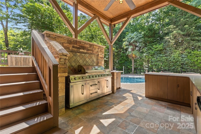 1336 Dobson Dr, Waxhaw, NC 28173 - view of patio featuring an outdoor kitchen, ceiling fan, an outdoor pool, stairs, and view of wooded area