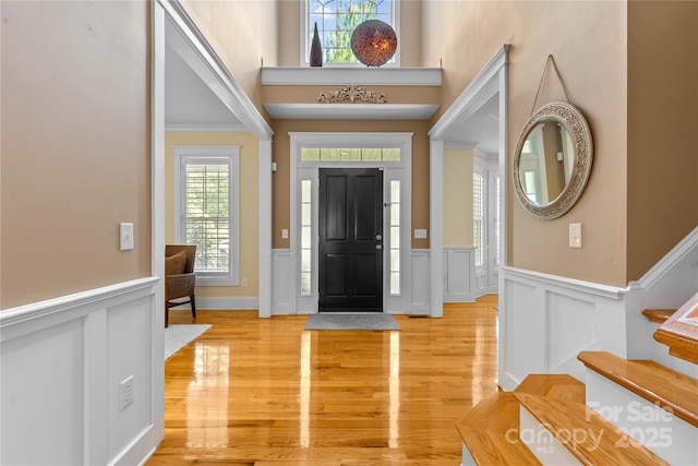 1336 Dobson Dr, Waxhaw, NC 28173 - entryway featuring a wainscoted wall, light wood-type flooring, stairs, a decorative wall, and a towering ceiling