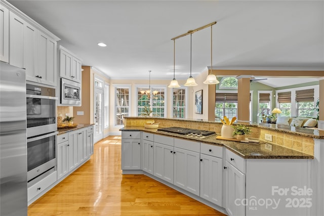 1336 Dobson Dr, Waxhaw, NC 28173 - kitchen with stainless steel appliances, crown molding, light wood-style floors, decorative backsplash, and white cabinets