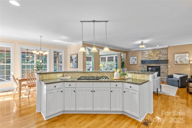 1336 Dobson Dr, Waxhaw, NC 28173 - kitchen featuring stainless steel gas stovetop, a fireplace, open floor plan, healthy amount of natural light, and crown molding