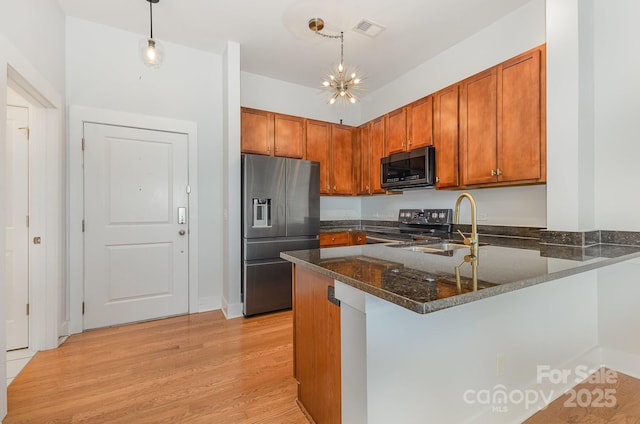 3271 Noda Blvd, Charlotte, NC 28205 - kitchen with appliances with stainless steel finishes, a peninsula, brown cabinetry, and dark stone counters