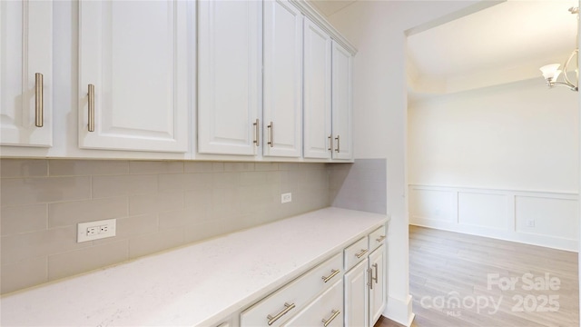 7651 Fenn Way, Fort Mill, SC 29707 - kitchen with white cabinets, a chandelier, decorative backsplash, wainscoting, and light wood-style floors