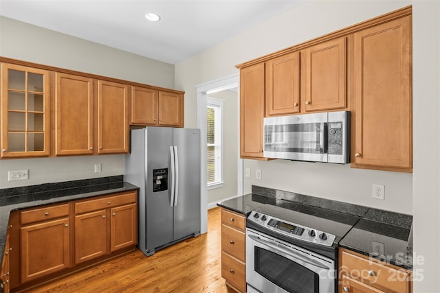 187 Water Oak Dr, Mooresville, NC 28117 - kitchen featuring appliances with stainless steel finishes, light wood finished floors, dark stone countertops, glass insert cabinets, and recessed lighting