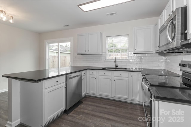7806 Mcgarry Trl, Charlotte, NC 28214 - kitchen featuring stainless steel appliances, a peninsula, dark countertops, dark wood-type flooring, and decorative backsplash