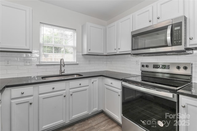 7806 Mcgarry Trl, Charlotte, NC 28214 - kitchen featuring appliances with stainless steel finishes, decorative backsplash, wood finished floors, white cabinetry, and dark stone counters