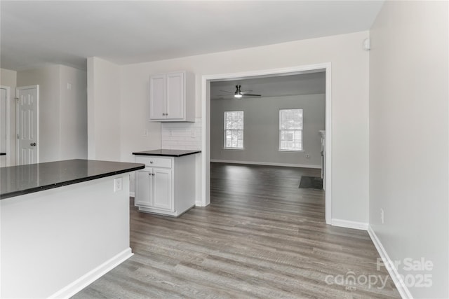 7806 Mcgarry Trl, Charlotte, NC 28214 - kitchen with dark countertops, light wood-style flooring, white cabinets, and a ceiling fan